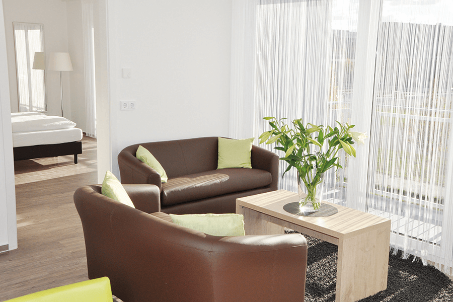 Sitzbereich mit Sofas, große helle Fenster - prämiertes Serviced Apartment in Berlin für Urlaub oder Business